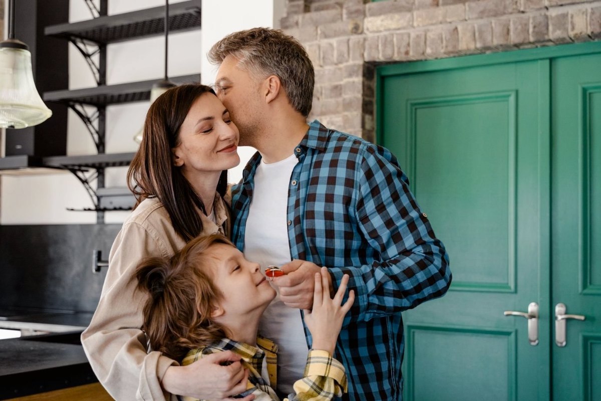 A family at their front door, the son holding the keys to their new home