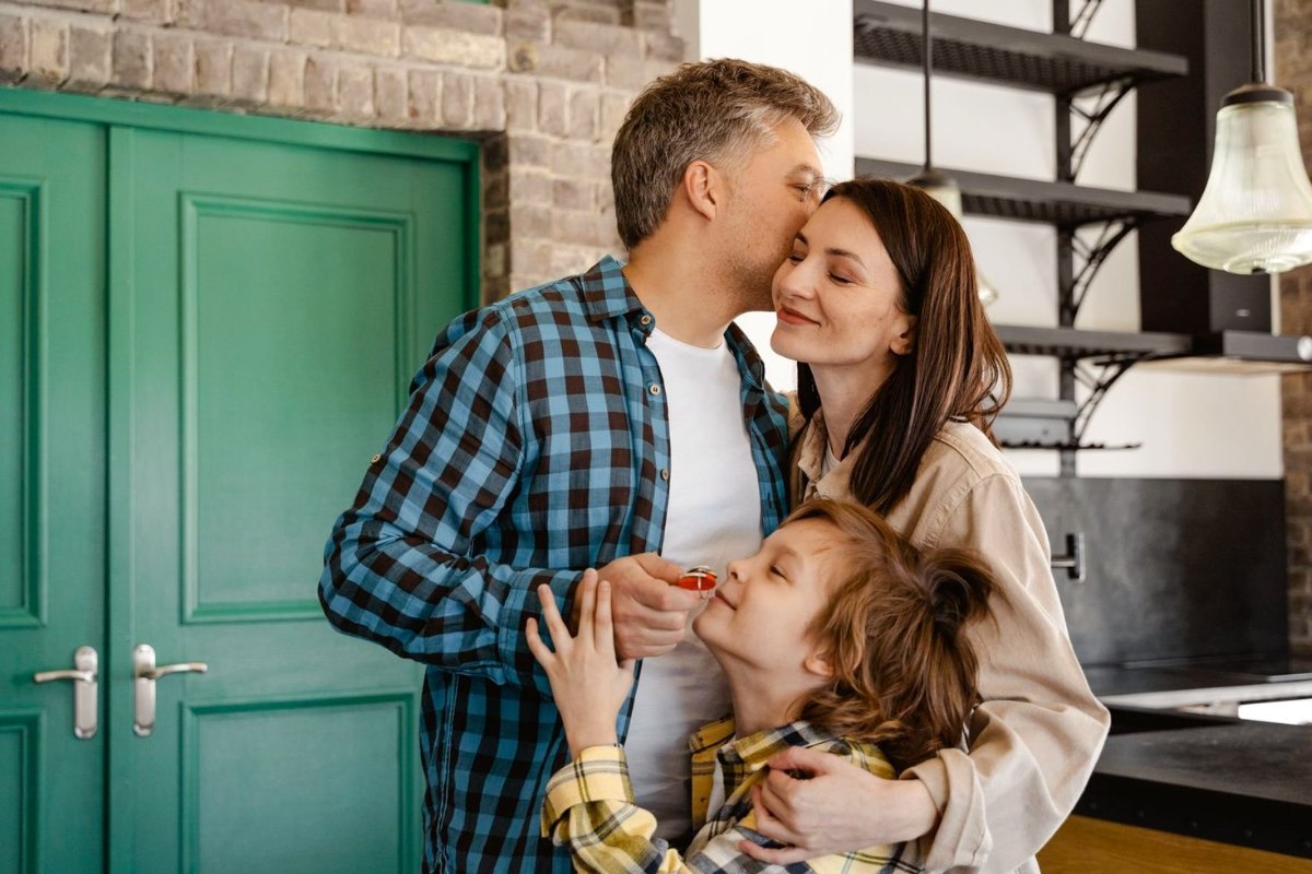 A family at their front door, the son holding the keys to their new home