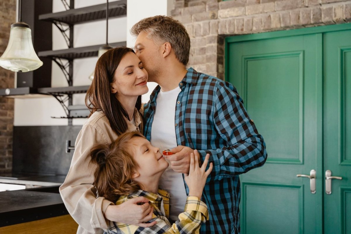A family at their front door, the son holding the keys to their new home