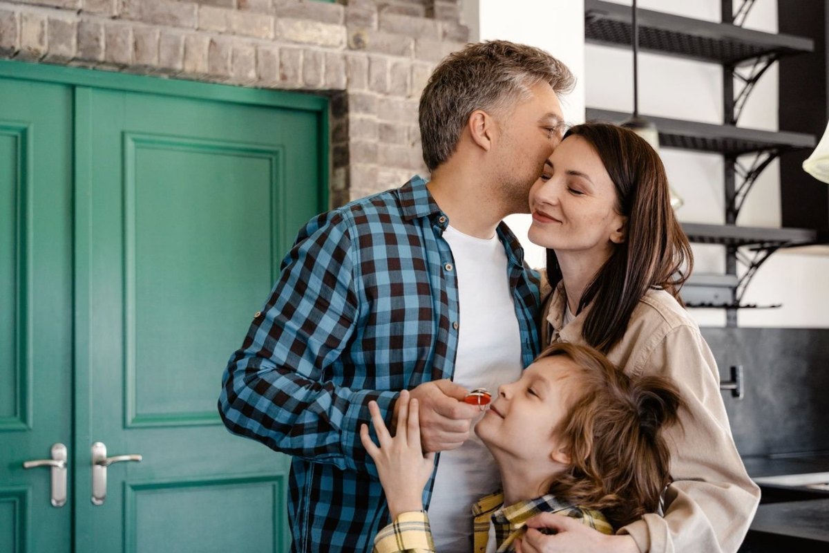 A family at their front door, the son holding the keys to their new home