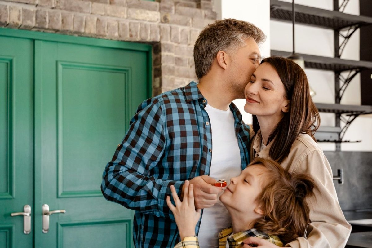 A family at their front door, the son holding the keys to their new home