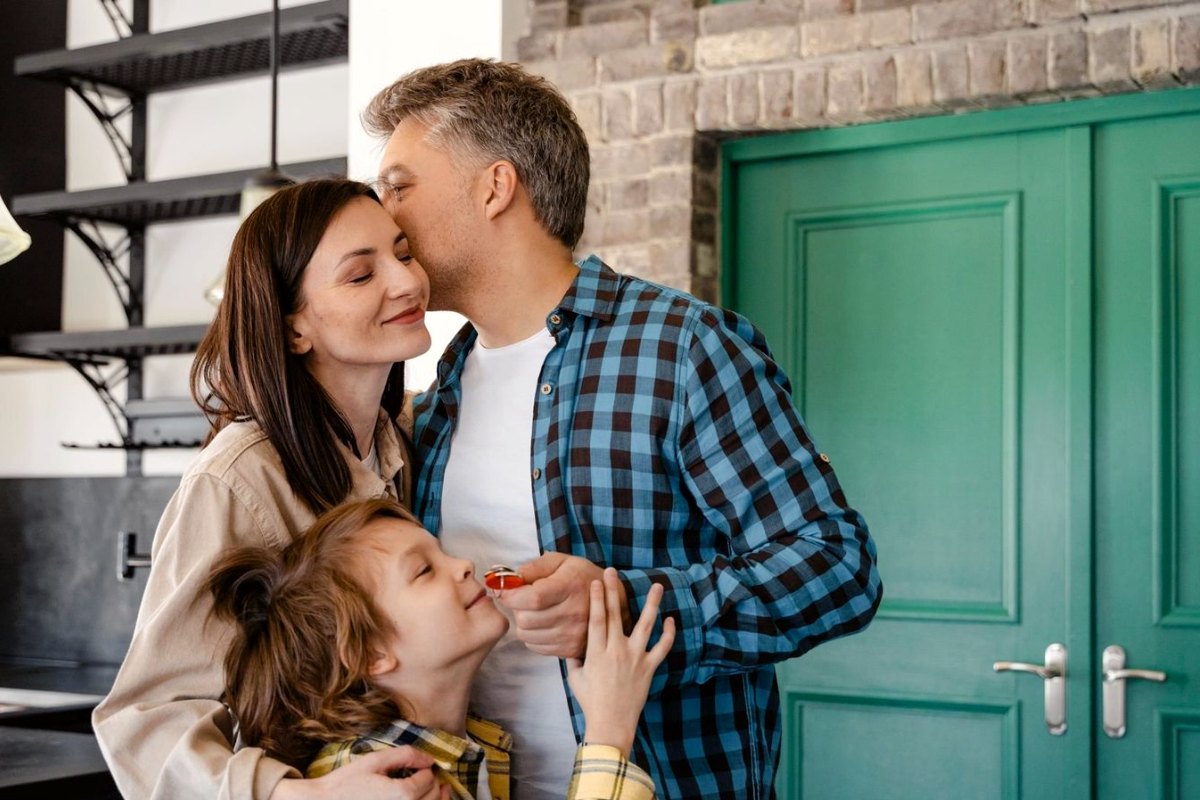 A family at their front door, the son holding the keys to their new home
