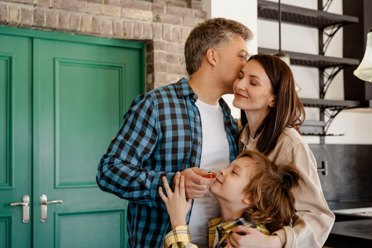 A family at their front door, the son holding the keys to their new home
