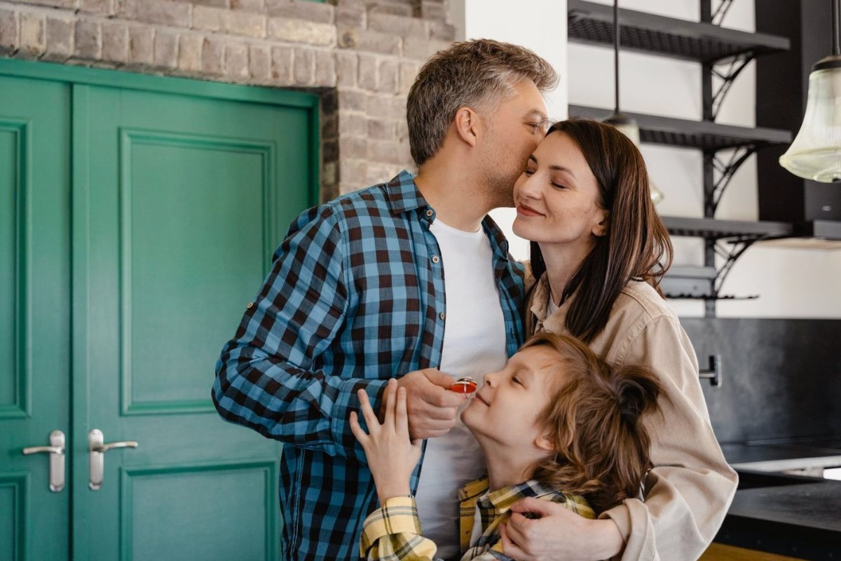 A family at their front door, the son holding the keys to their new home