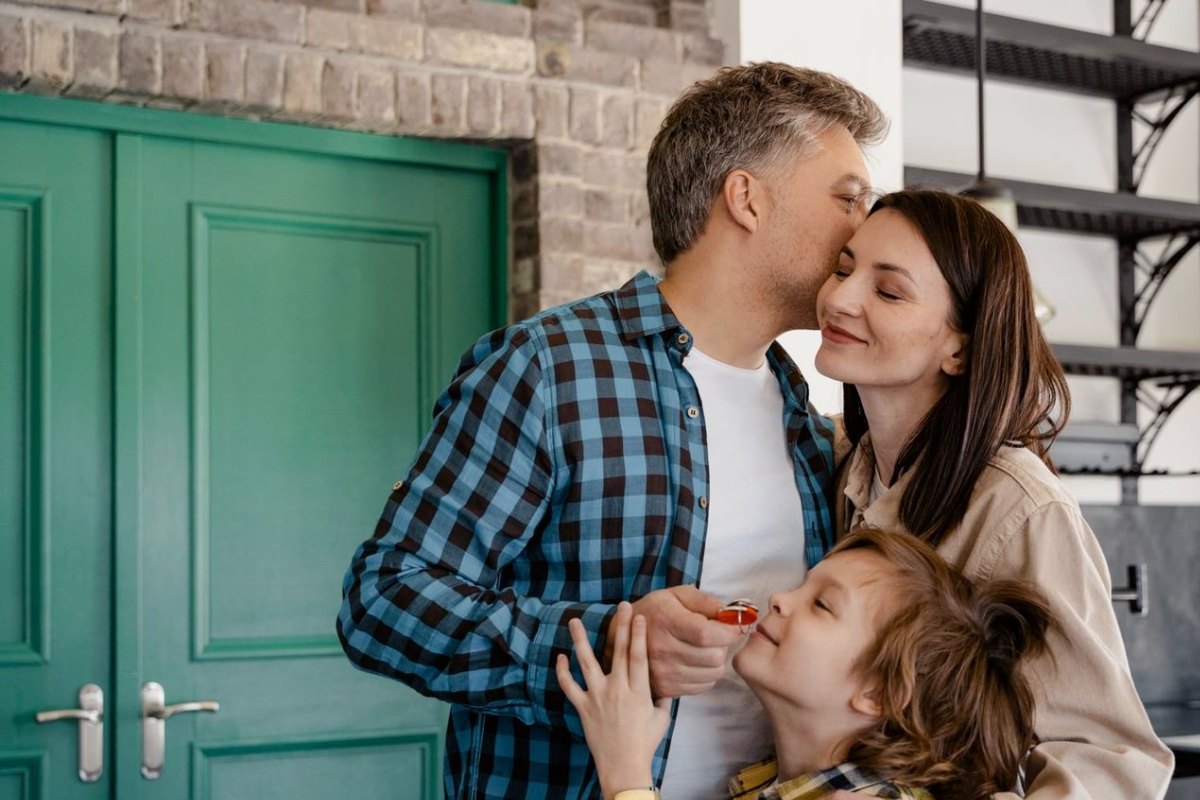 A family at their front door, the son holding the keys to their new home