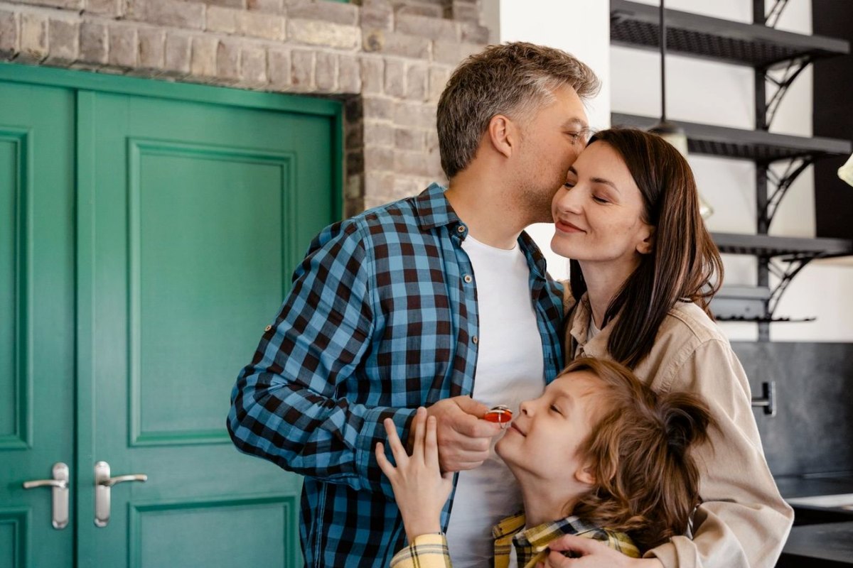 A family at their front door, the son holding the keys to their new home