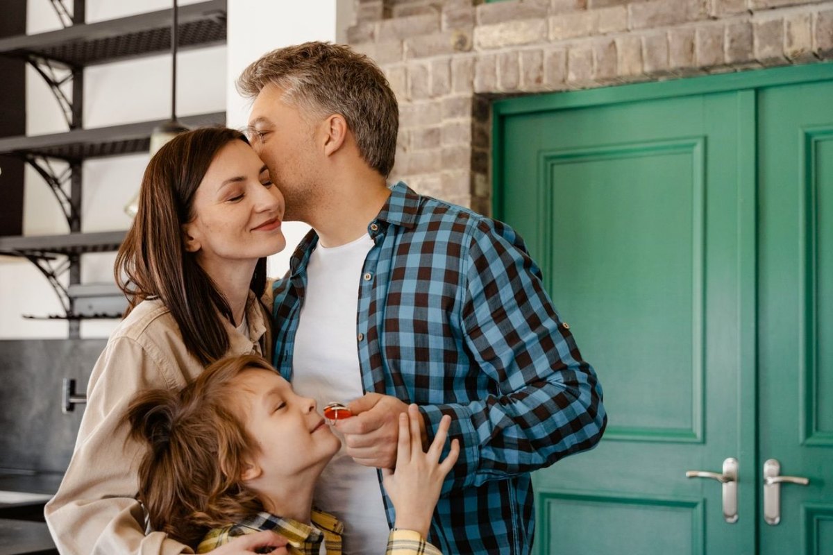 A family at their front door, the son holding the keys to their new home