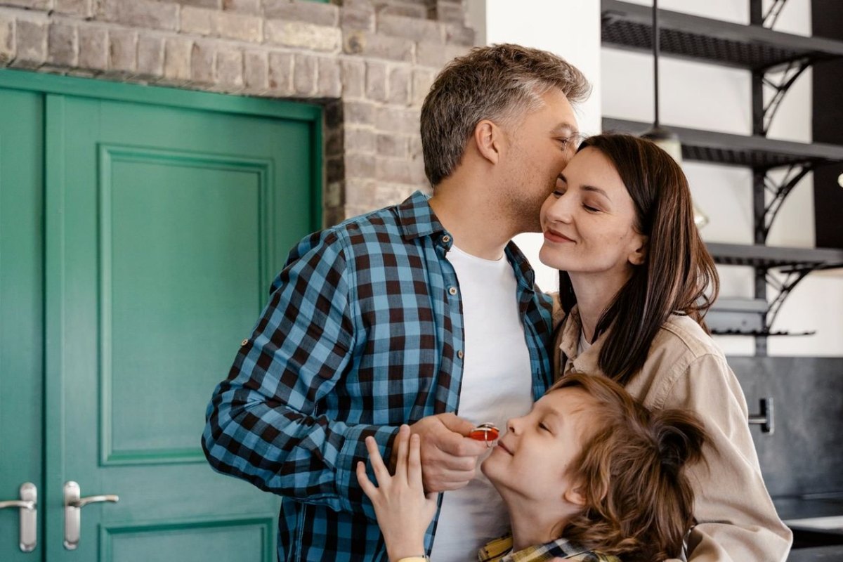 A family at their front door, the son holding the keys to their new home