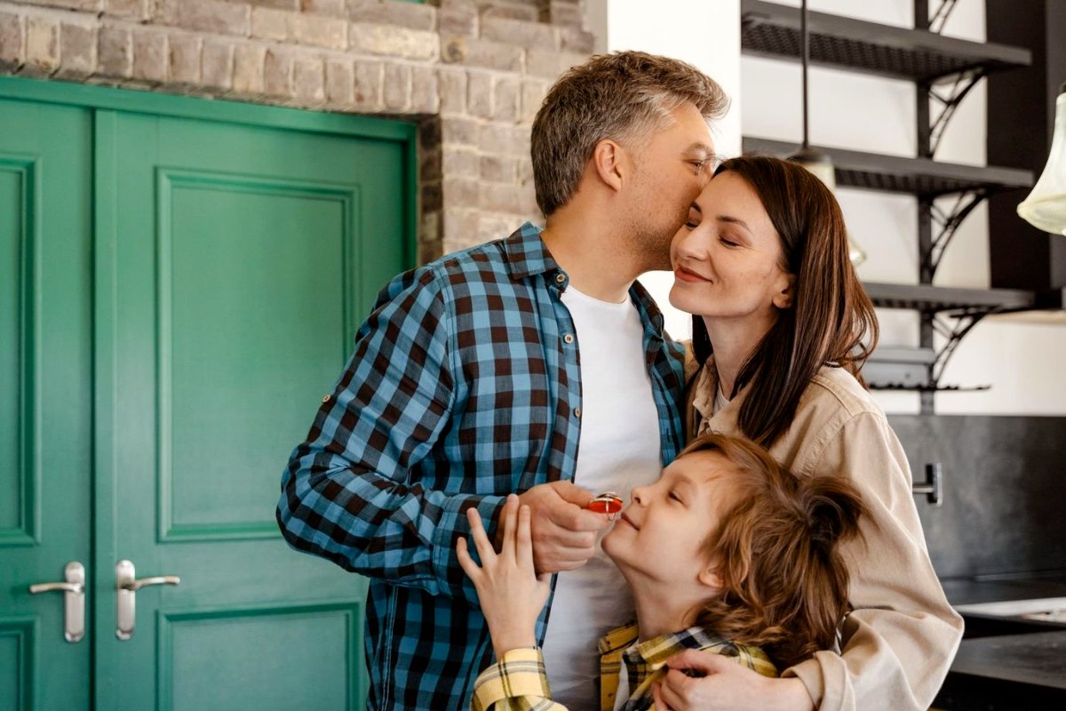A family at their front door, the son holding the keys to their new home