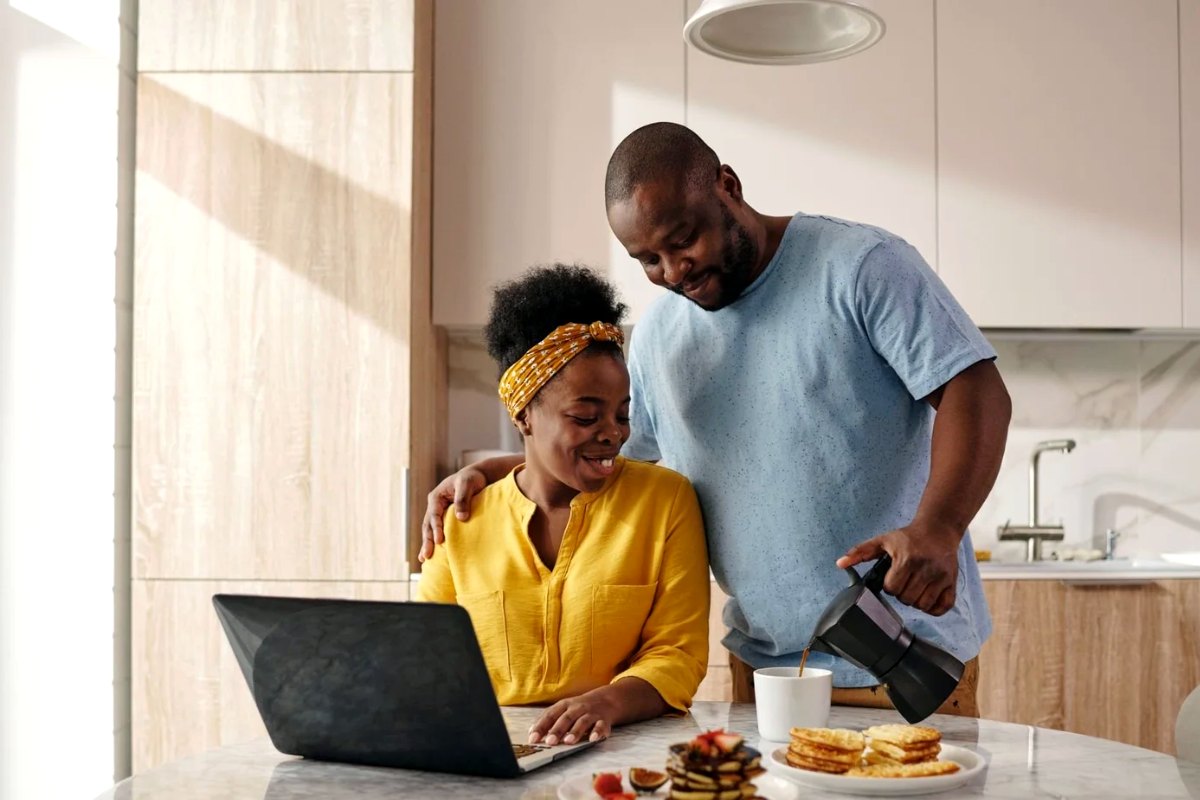 A couple checking rates on a laptop in their kitchen