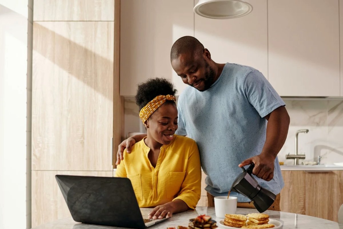 A couple checking rates on a laptop in their kitchen