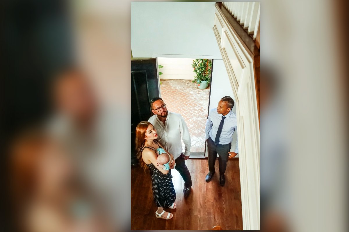 A young family with a baby walking into a home